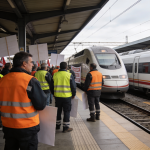Trabajadores ferroviarios con chalecos reivindicativos ante un tren detenido en andén